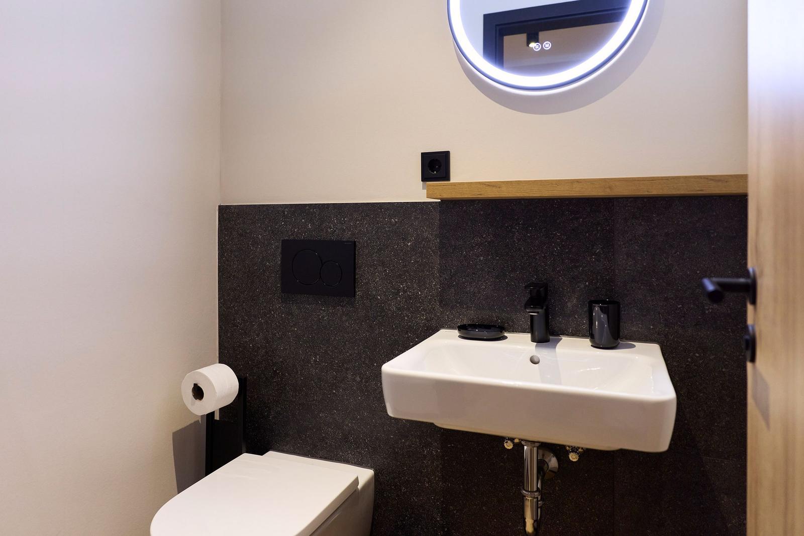 Badezimmer mit Waschbecken, Spiegel und Toilette.
