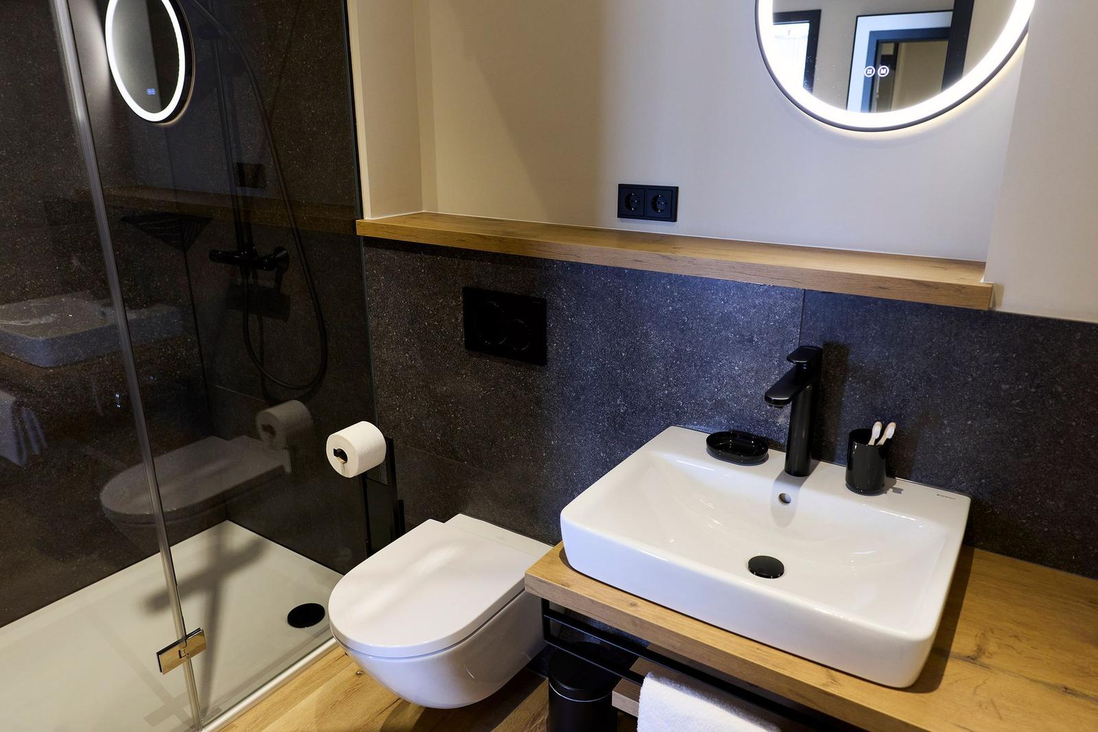 Bad mit Dusche, Toilette und Waschbecken auf Holzunterlage