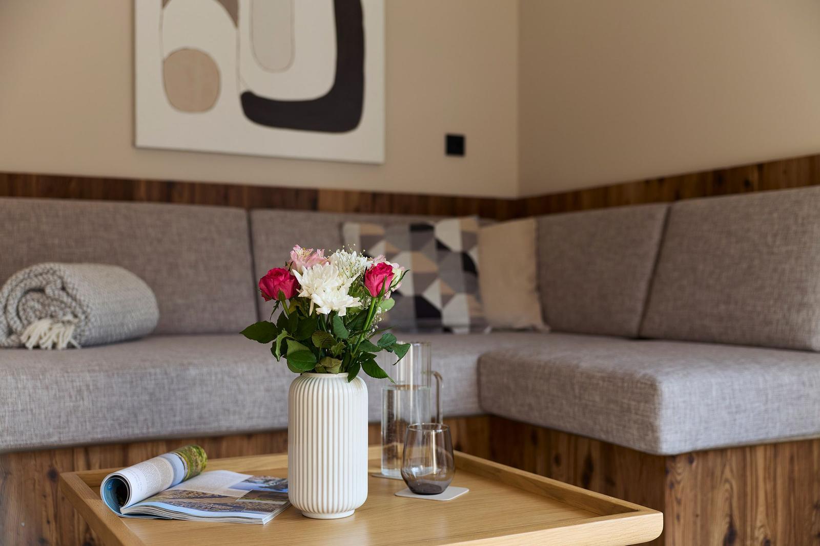 Ein Wohnbereich mit Sofa, Tisch und Blumenarrangement.