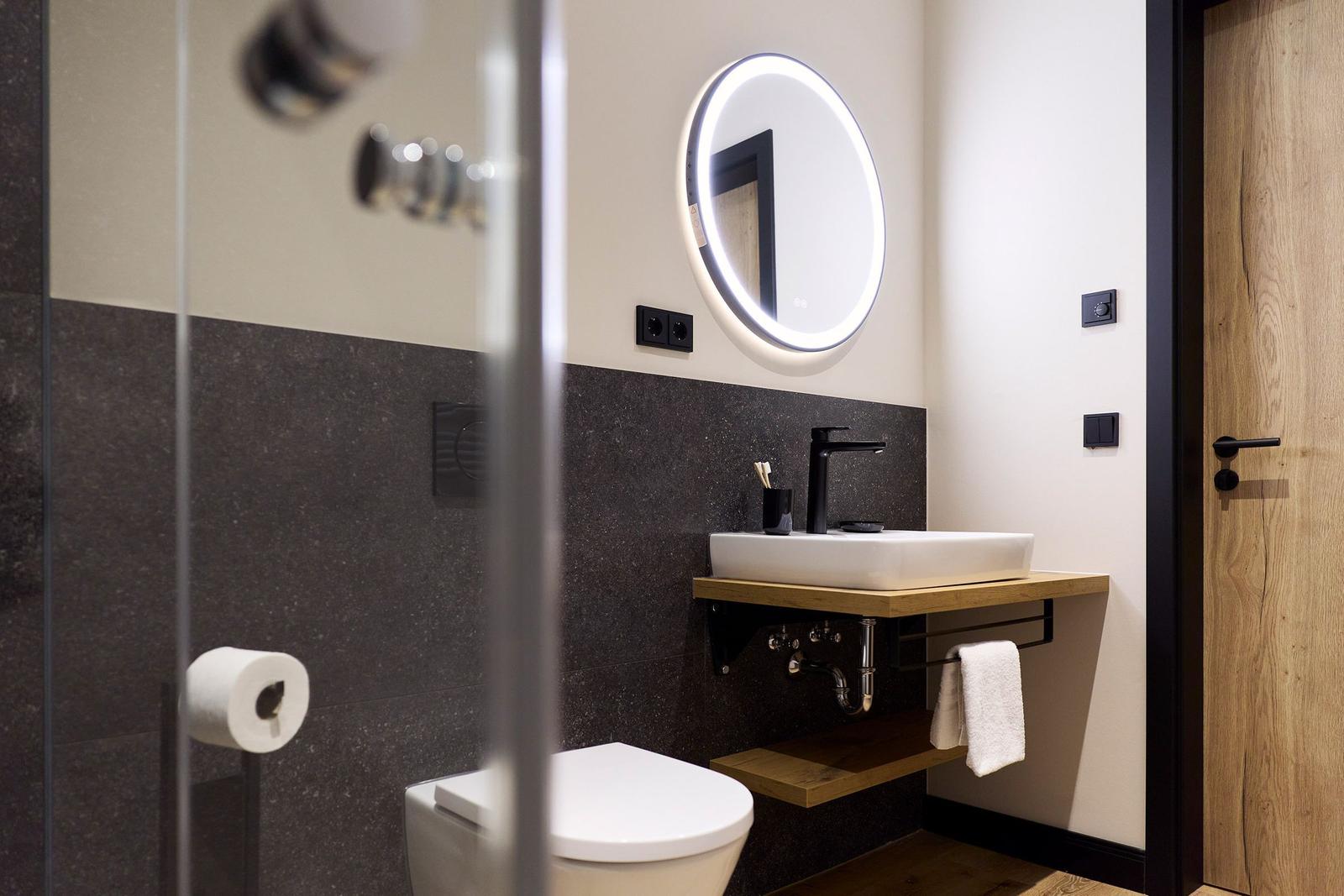 Badezimmer mit Waschbecken, Spiegel, Toilette und Dusche.