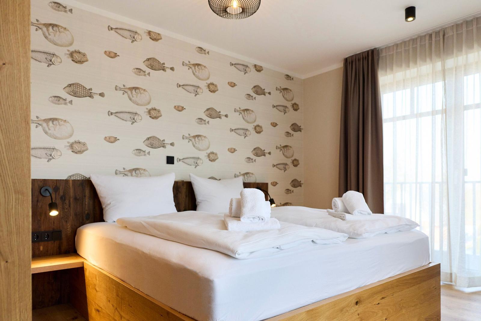 Schlafzimmer mit Bett, Fischtapete und Fenster mit Vorhängen.