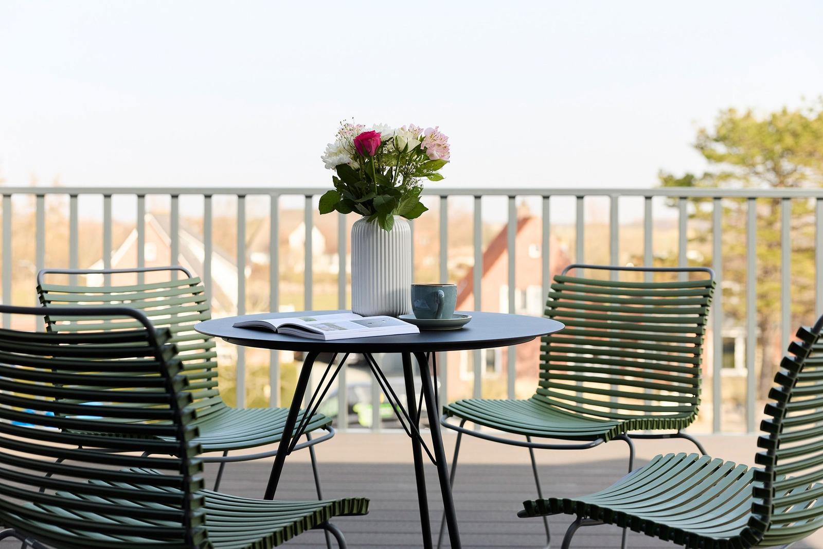 Terrasse mit Tisch, Stühlen und Blumenarrangement. Blick auf Wohngebiet.