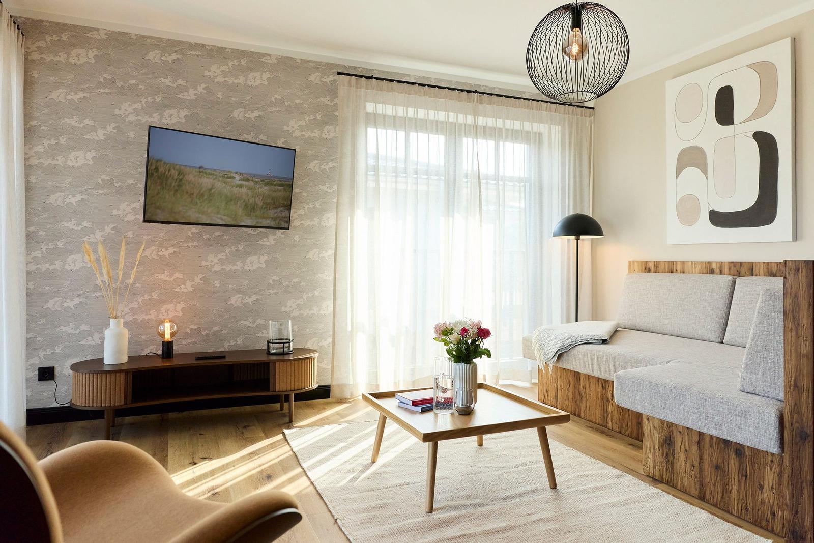 Wohnzimmer mit Sofa, Couchtisch und Fernseher an der Wand.