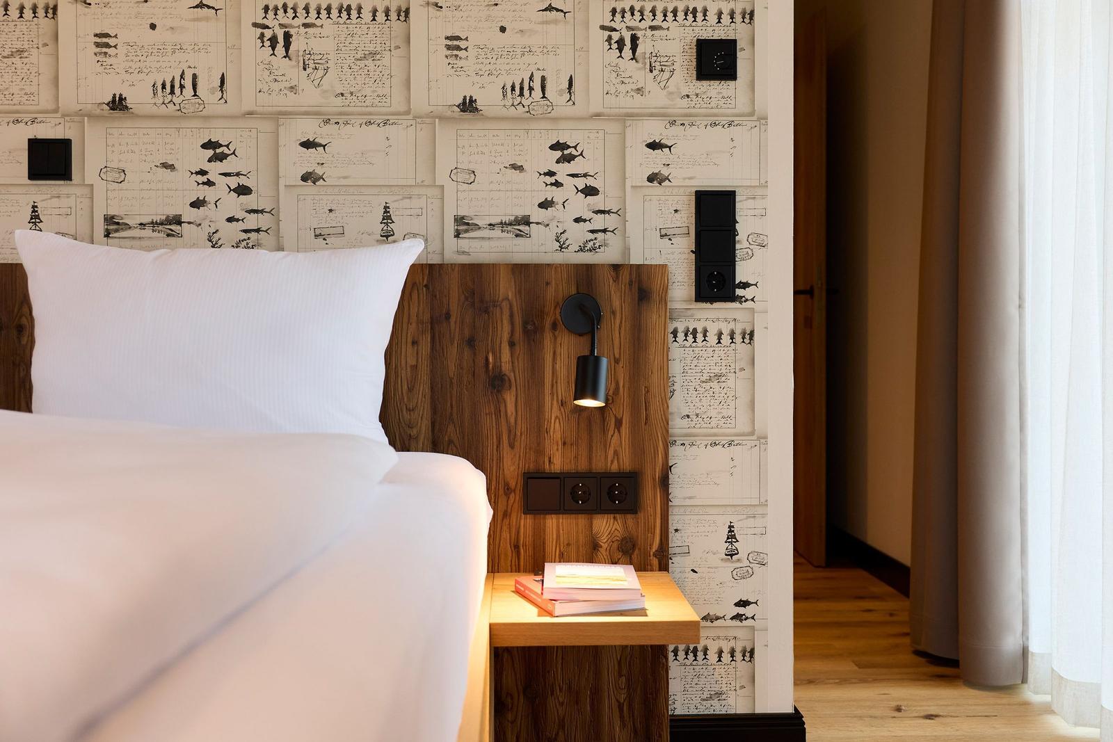 Schlafzimmer mit Bett, Nachttisch und dekorativer Wandverkleidung.
