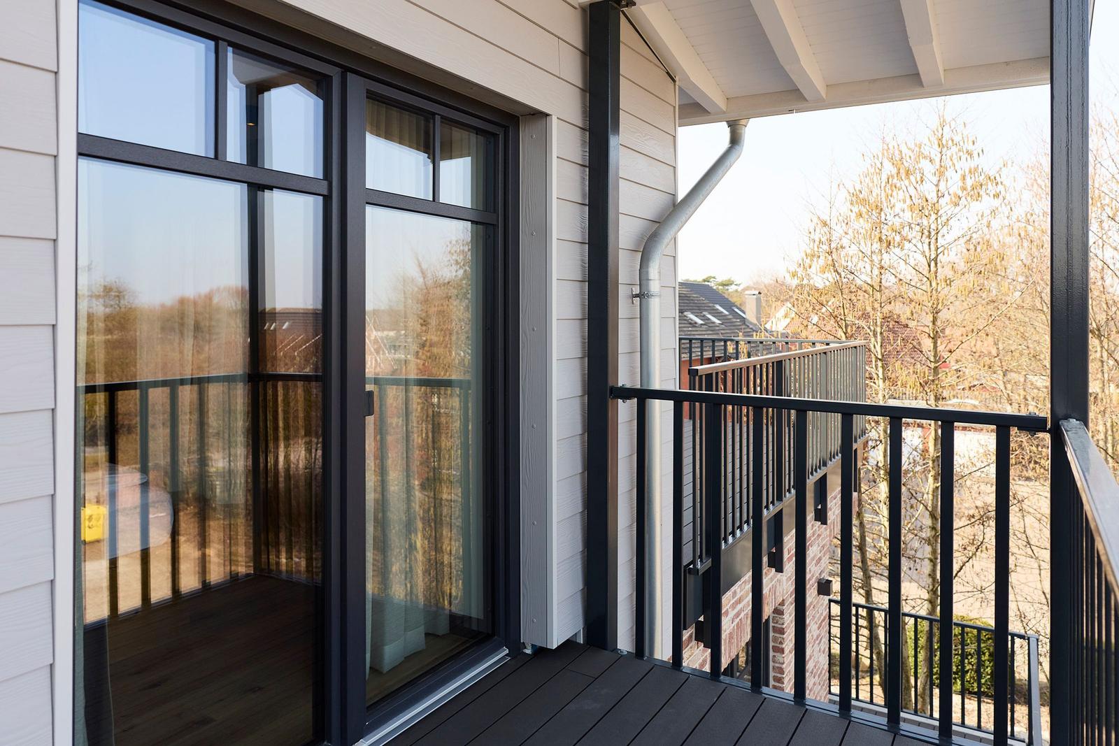 Terrasse mit Glas-Tür und Blick auf Bäume und Gebäude