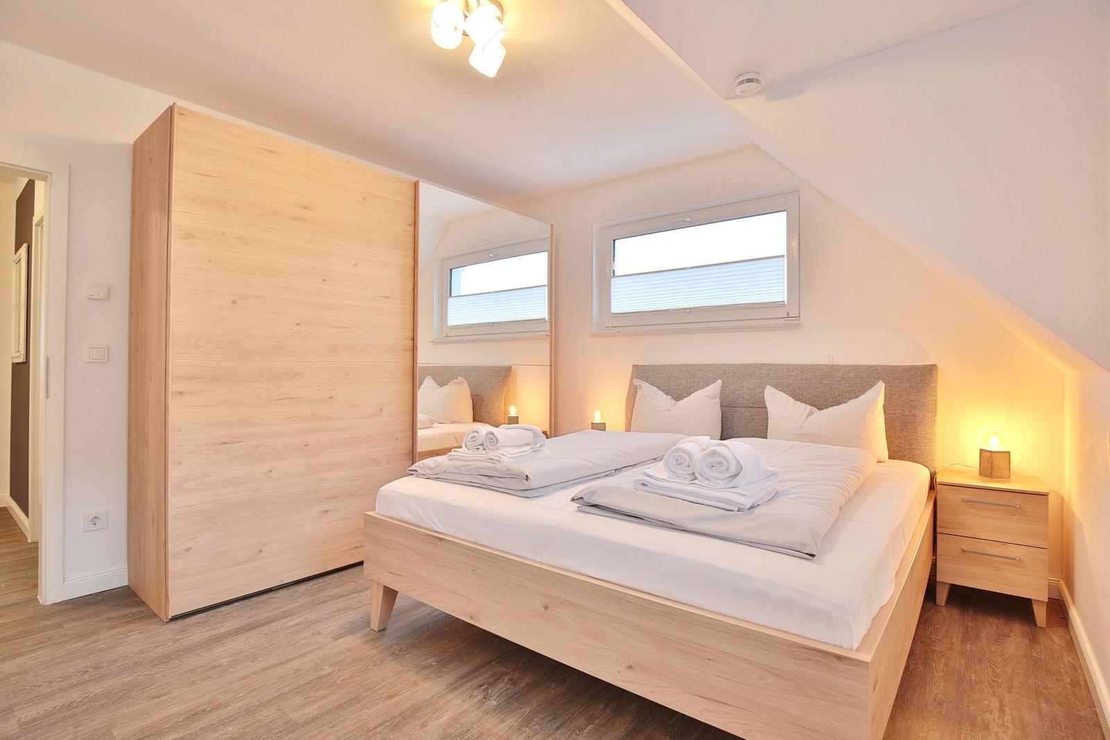 Schlafzimmer mit Doppelbett, Kleiderschrank und Nachttisch unter Dachschräge.