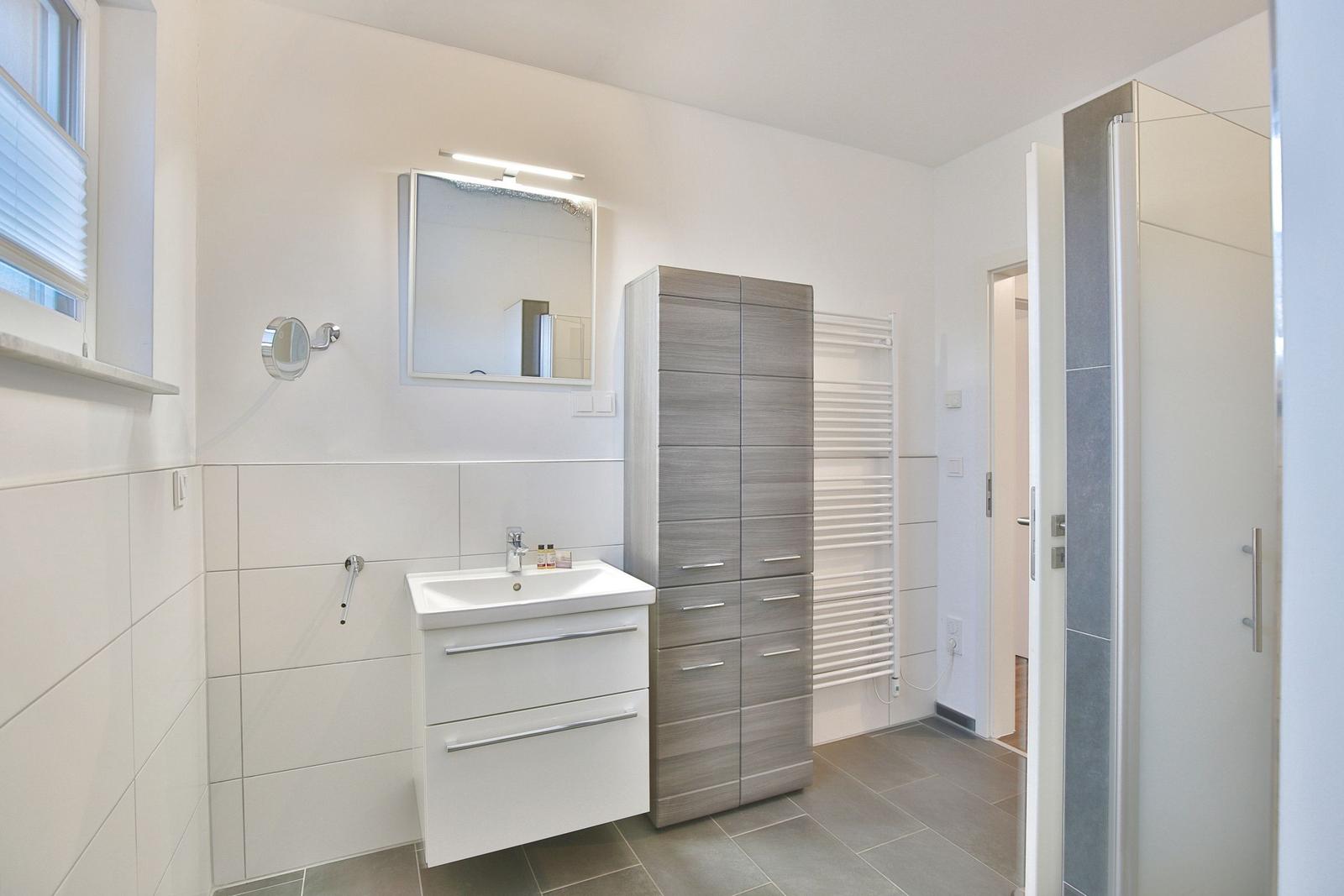 Badezimmer mit Waschbecken, Spiegel und Duschkabine.