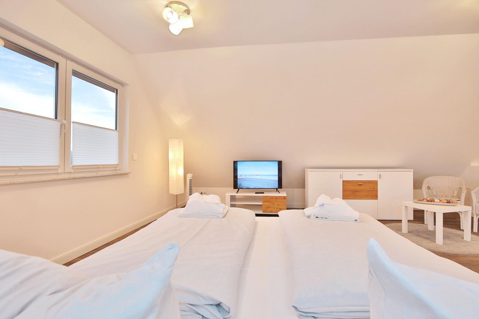 Zwei Betten, Fernseher und Schrank im Schlafzimmer mit Fenster.