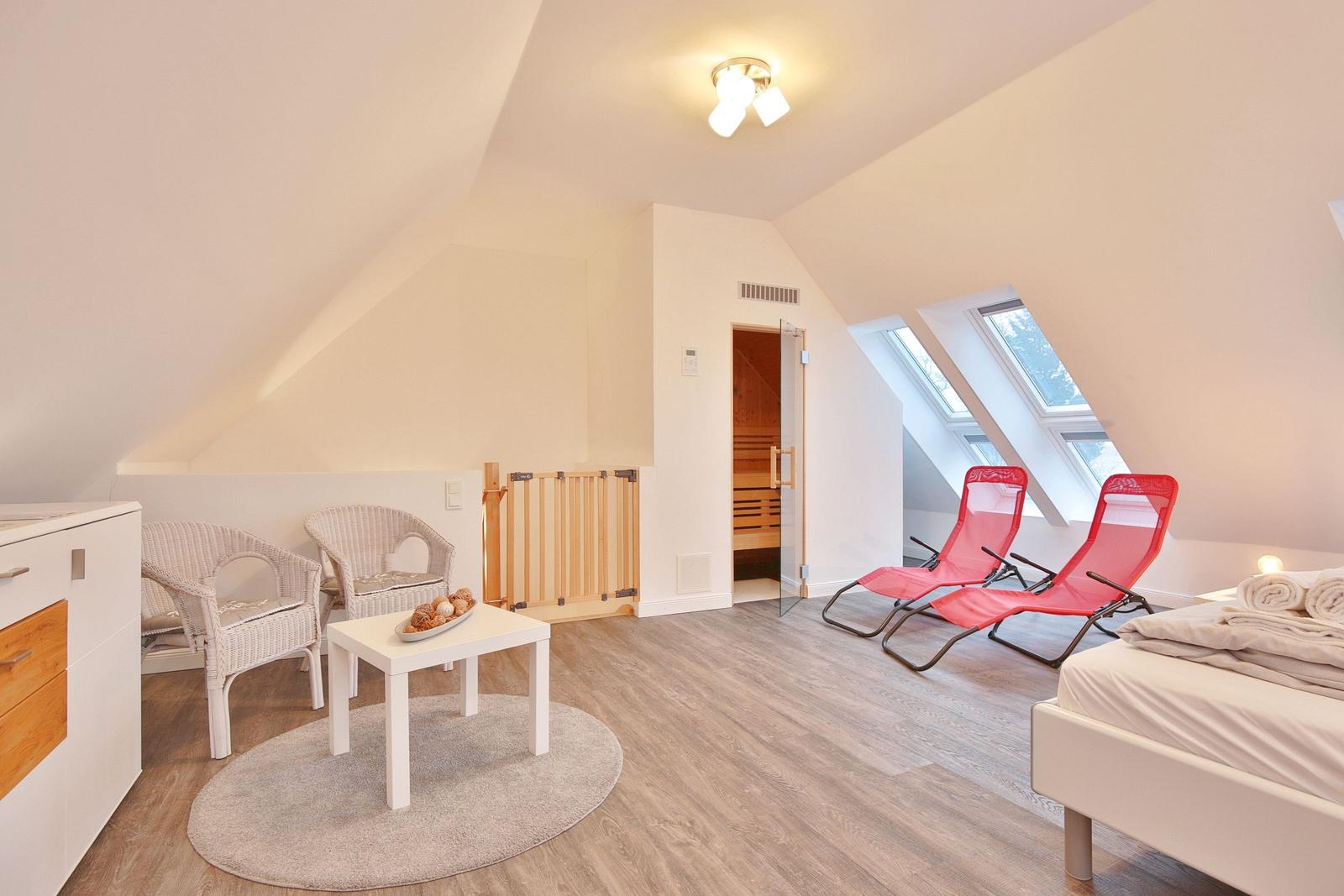 Schlafzimmer mit Sauna, zwei roten Liegestühlen und Dachfenstern.