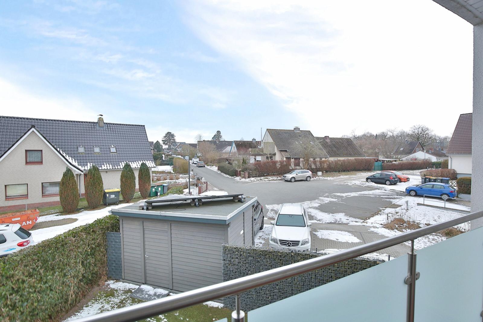 Blick von Balkon auf Straße mit Autos und Häusern im Winter