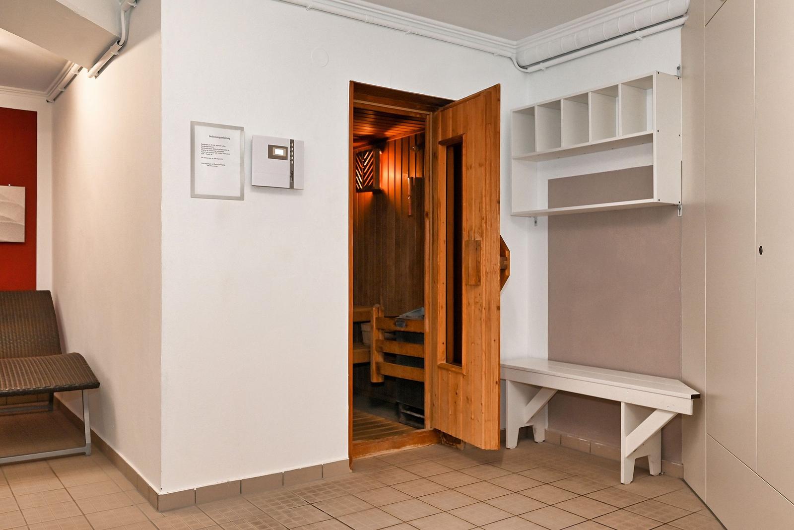 Sauna mit Holztür und Sitzbänken. Anschlussraum mit Bank und Regal.
