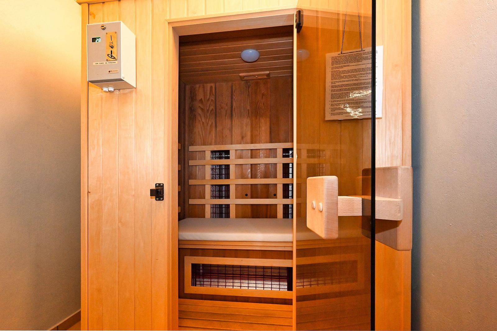 Eine Sauna mit Holzverkleidung, Sitzbank und digitaler Temperaturregelung an der Wand.