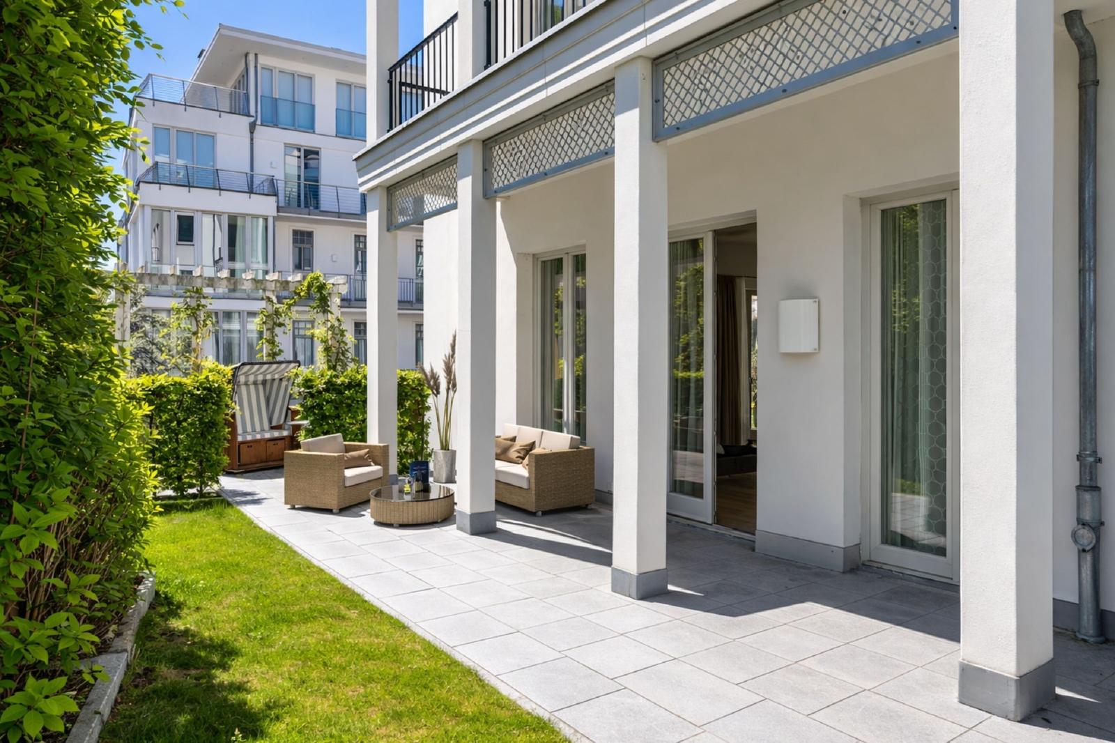 Terrasse mit Sitzgelegenheiten und Blick auf grünen Garten und Nachbarhaus.