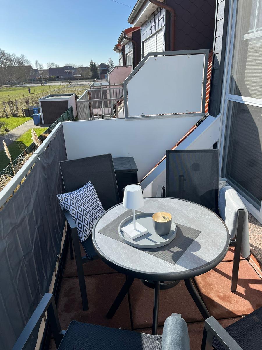 Terrasse mit runden Tisch, zwei Stühlen und Kaffeetasse. Blick auf grüne Landschaft.