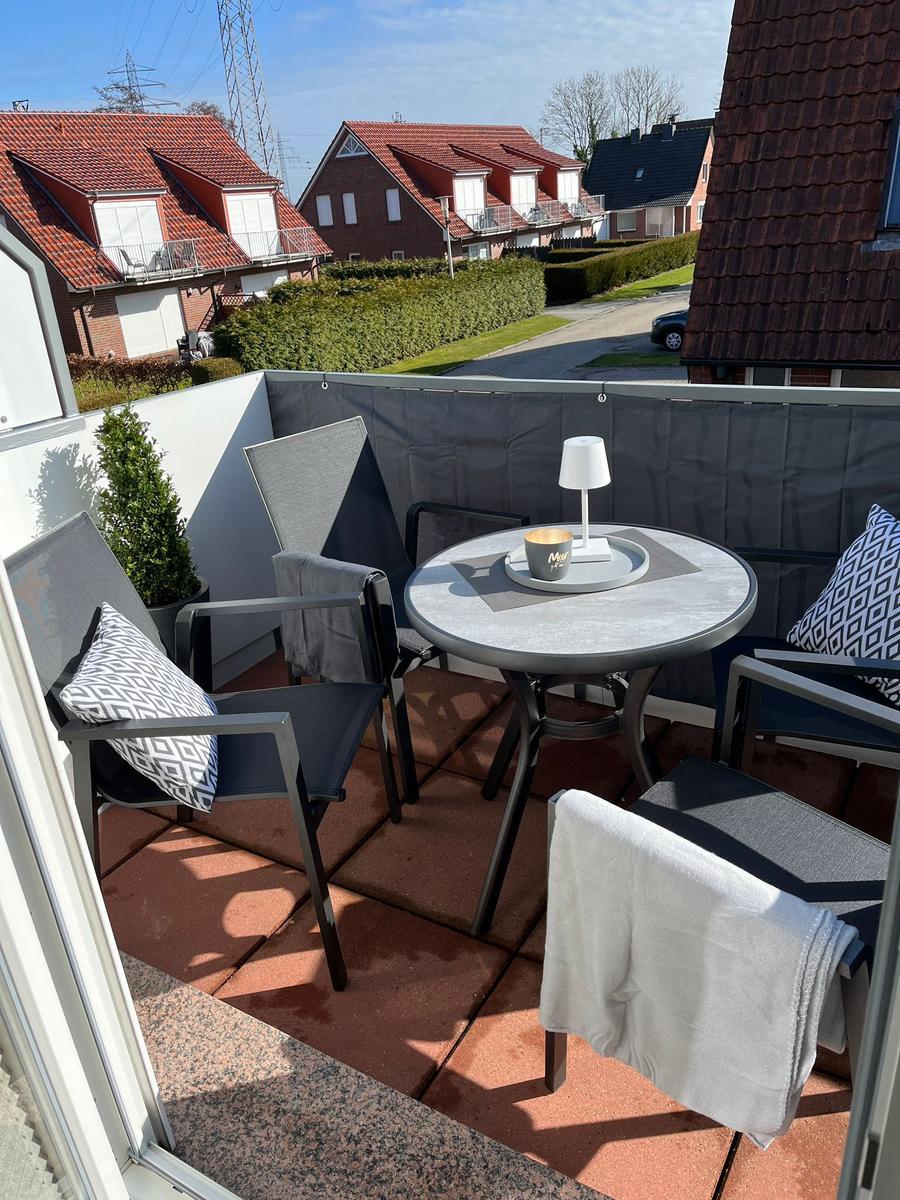 Terrasse mit Tisch, Stühlen und Bezug. Blick auf Wohnhäuser und Straße.
