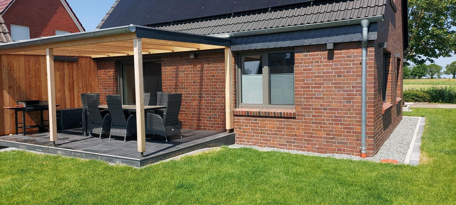 House with terrace, grill, and garden. Solar panels on roof.