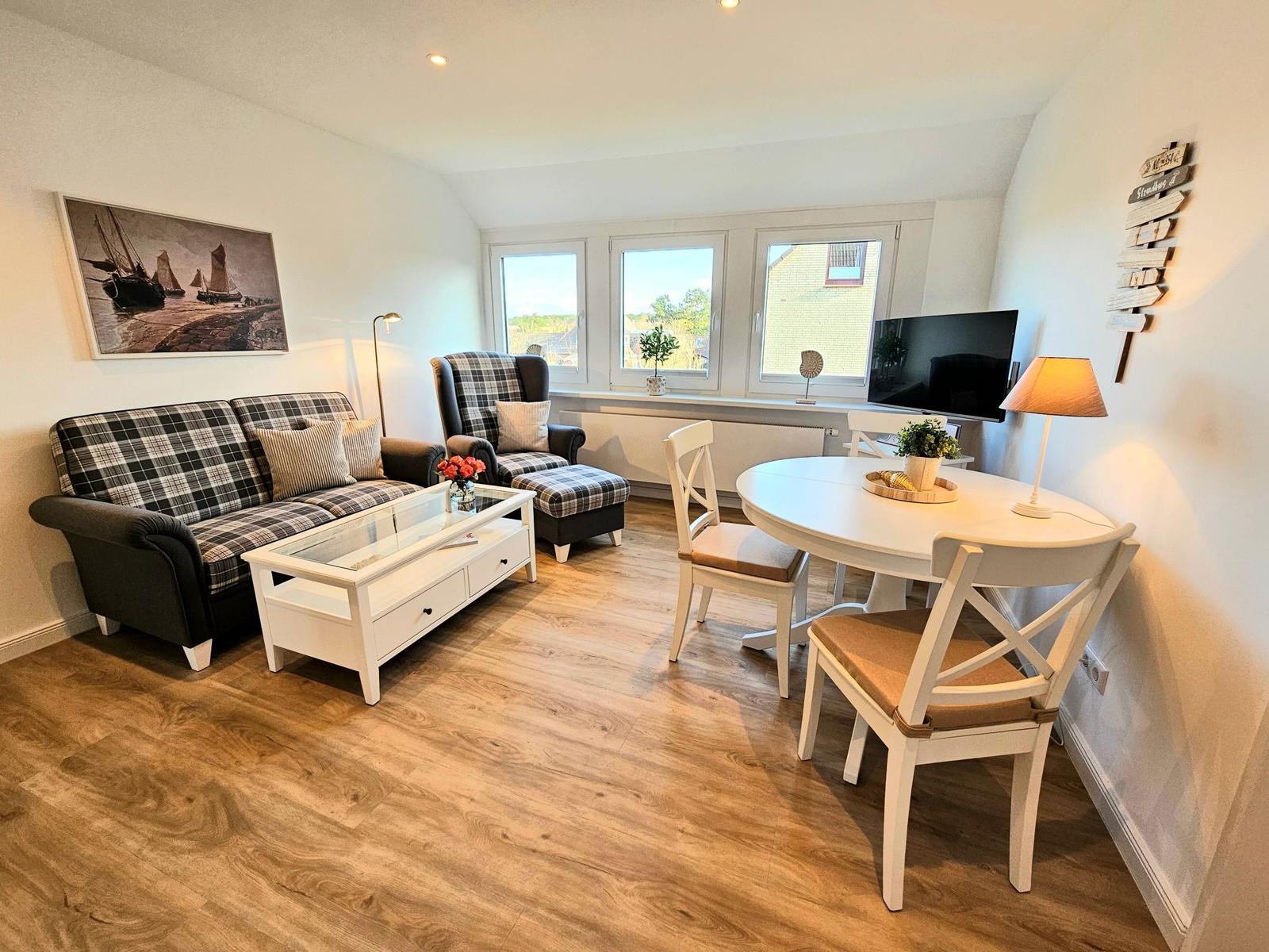 Wohn- und Essbereich mit Sofa, Esstisch und Fenstern.