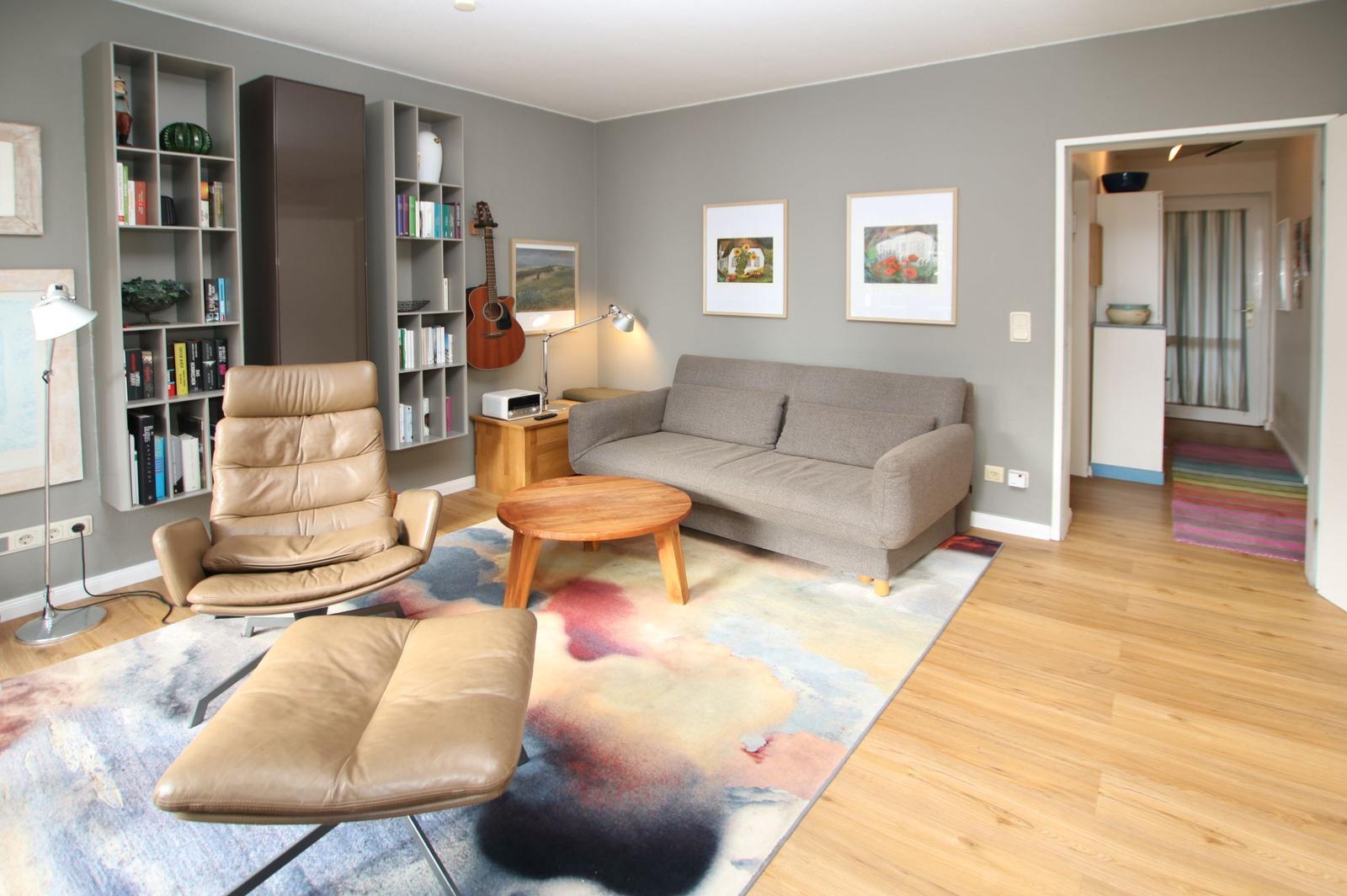 Wohnzimmer mit Sofa, Ledersessel und Bücherregalen an der Wand.