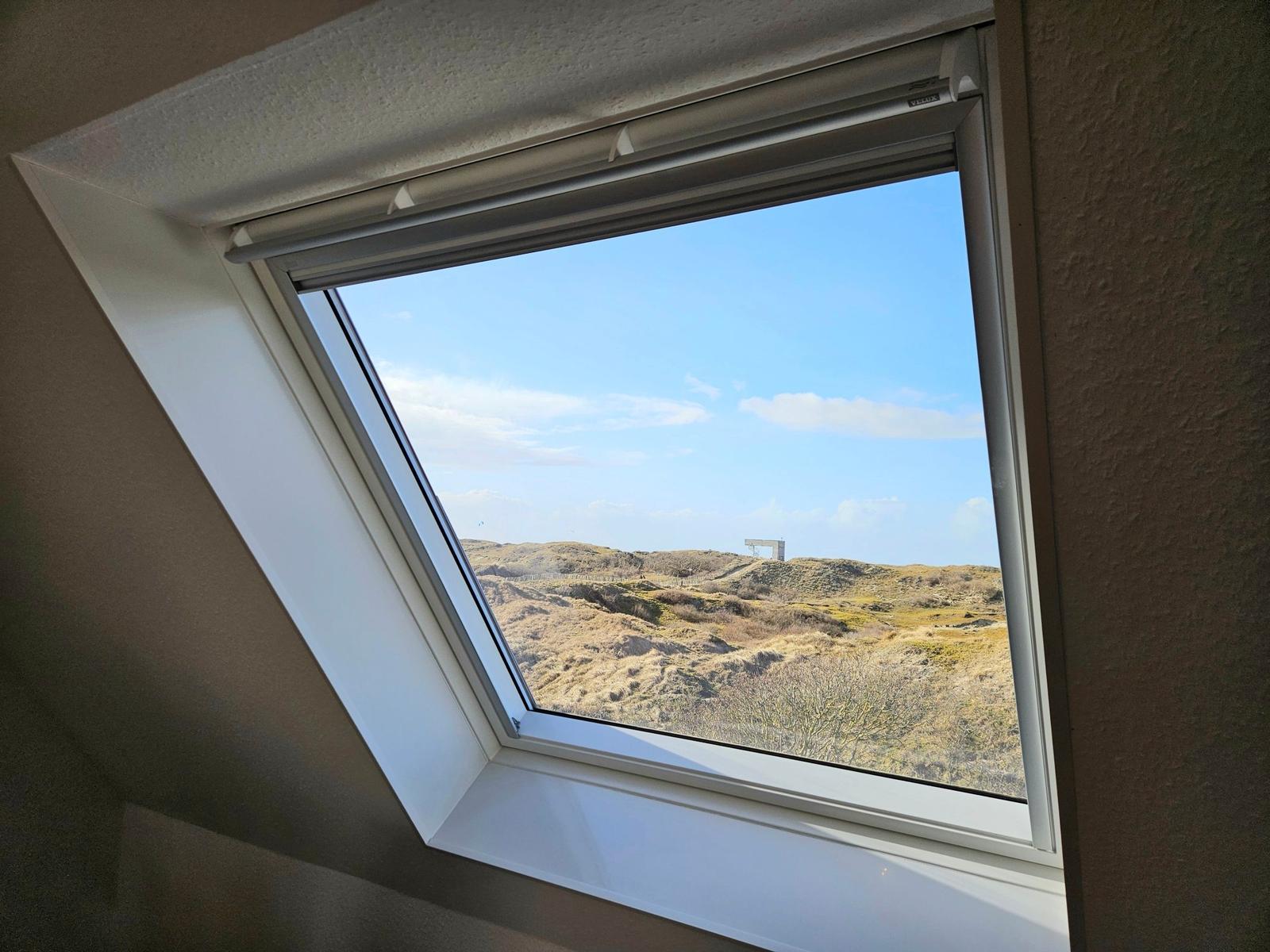 Dachfenster mit Blick auf Dünen und klaren Himmel