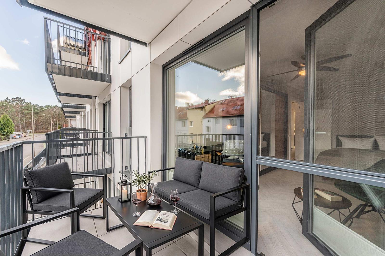 Terrasse mit Sitzgruppe und Tisch. Durchgehende Glasfront zum Innenraum.