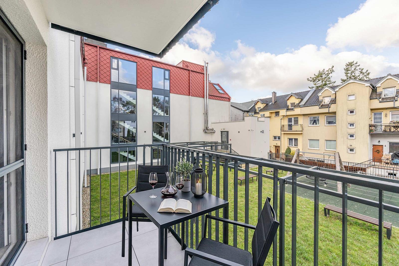 Terrasse mit Tisch, Stühlen und Pflanzen. Blick auf moderne und traditionelle Gebäude.