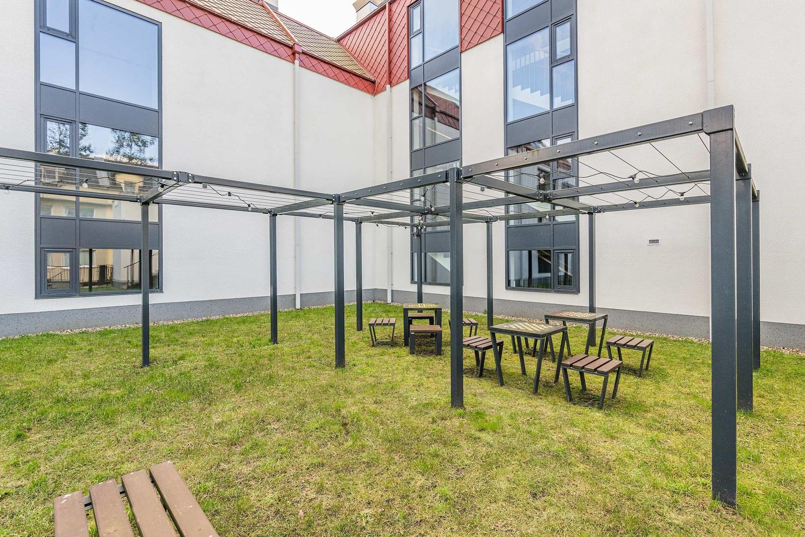 Hinterhof mit Grillplatz und Sitzgelegenheiten unter Pavillon.