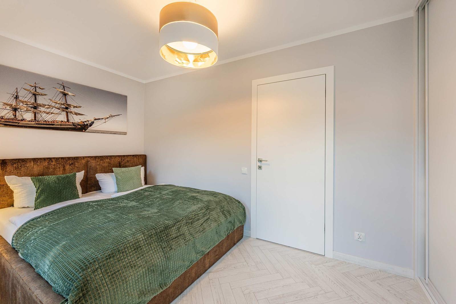 Schlafzimmer mit Bett, Wandbild und Deckenleuchte