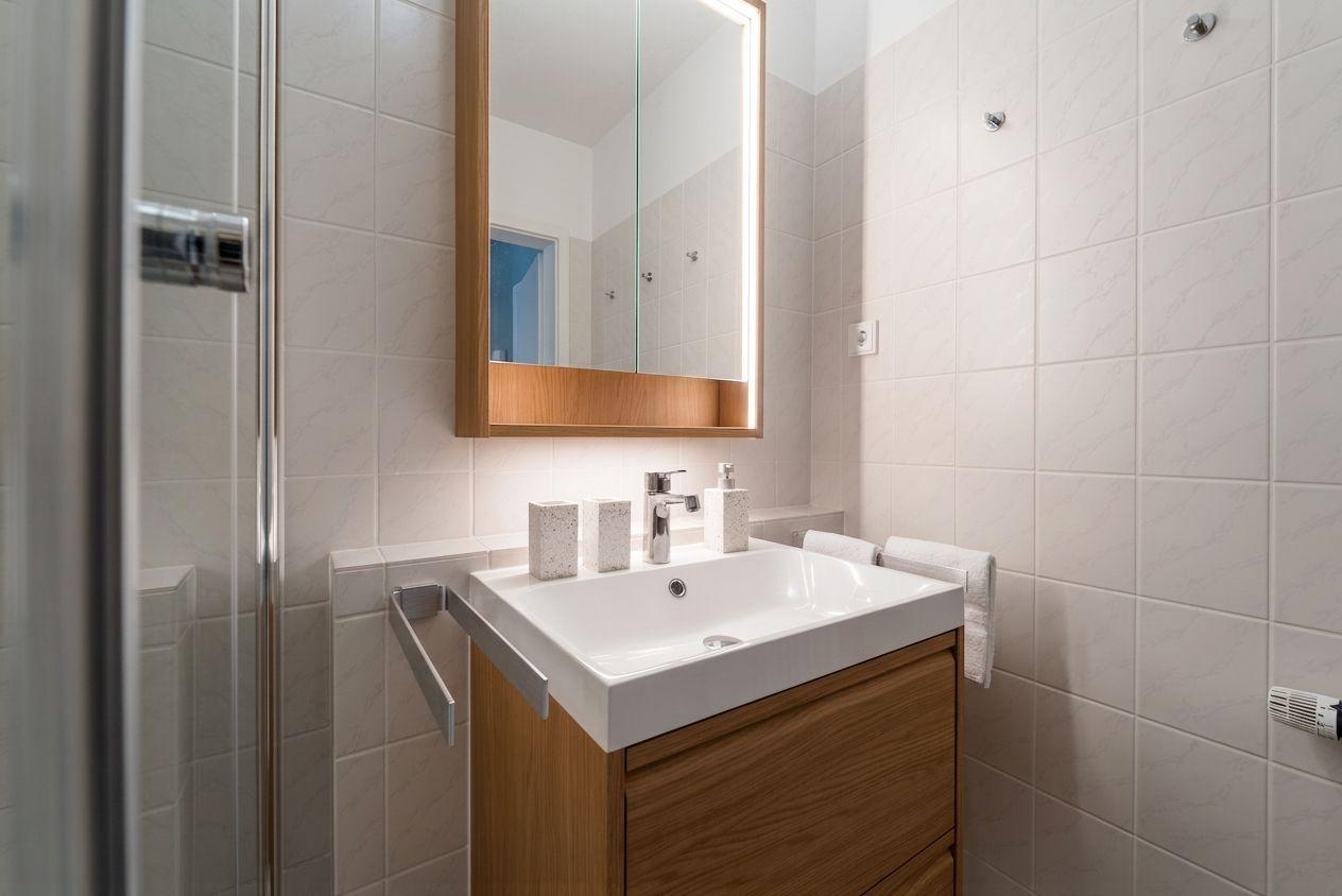 Badezimmer mit Waschbecken, Spiegel und Dusche.