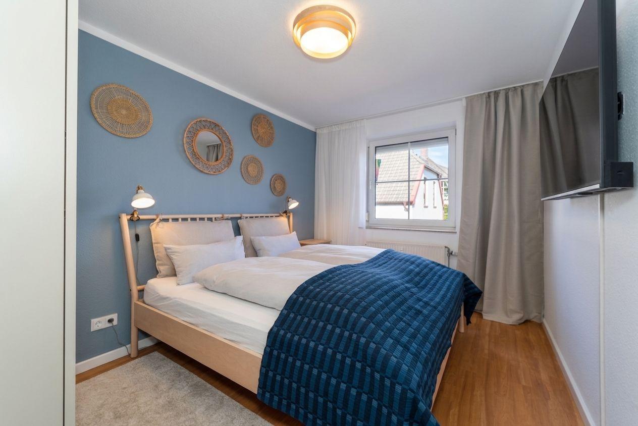 Schlafzimmer mit Bett, Fenster und Wanddekoration.