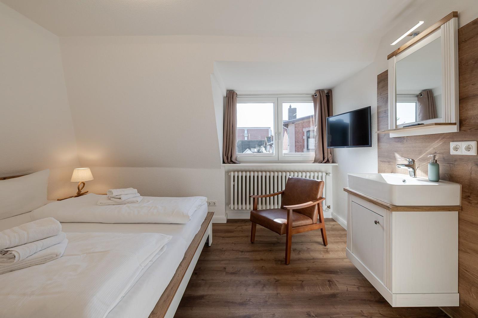 Zimmer mit Bett, Sessel, TV und Waschbecken