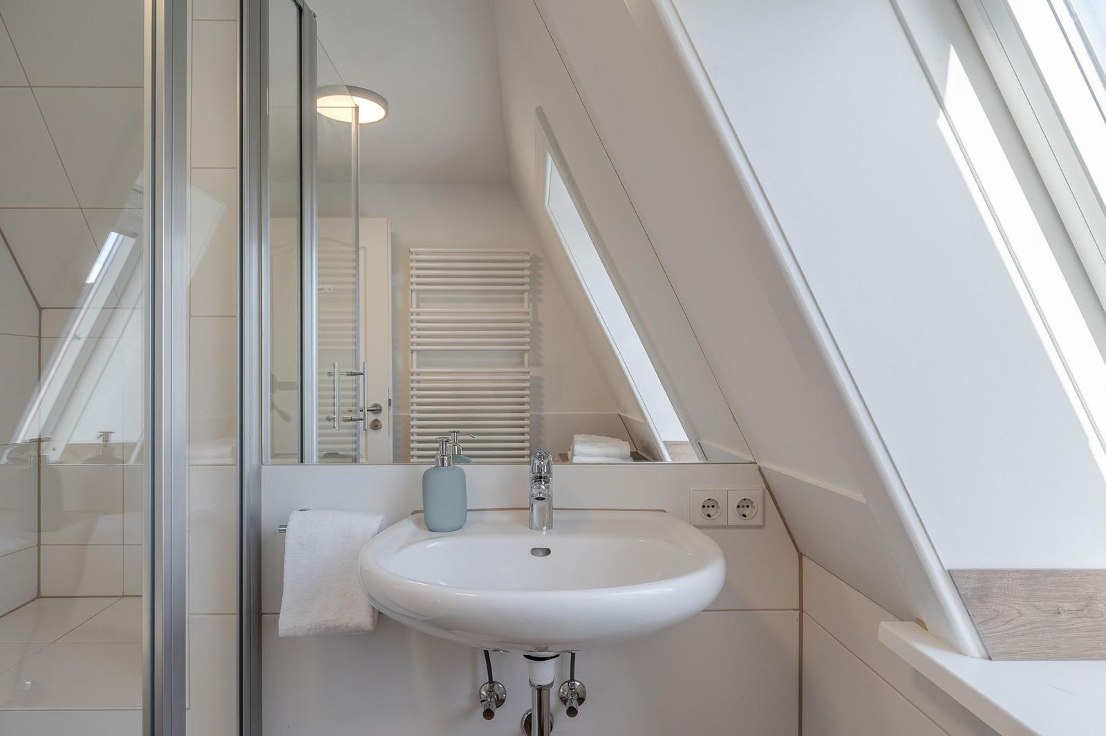 Badezimmer mit Duschabtrennung, Waschbecken und Dachfenster.