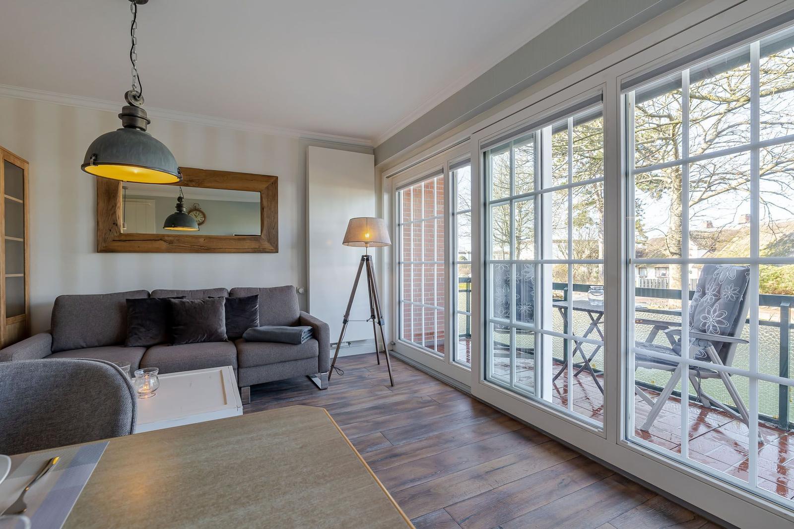 Wohnzimmer mit Sofa, Tisch und großem Fenster zur Terrasse.
