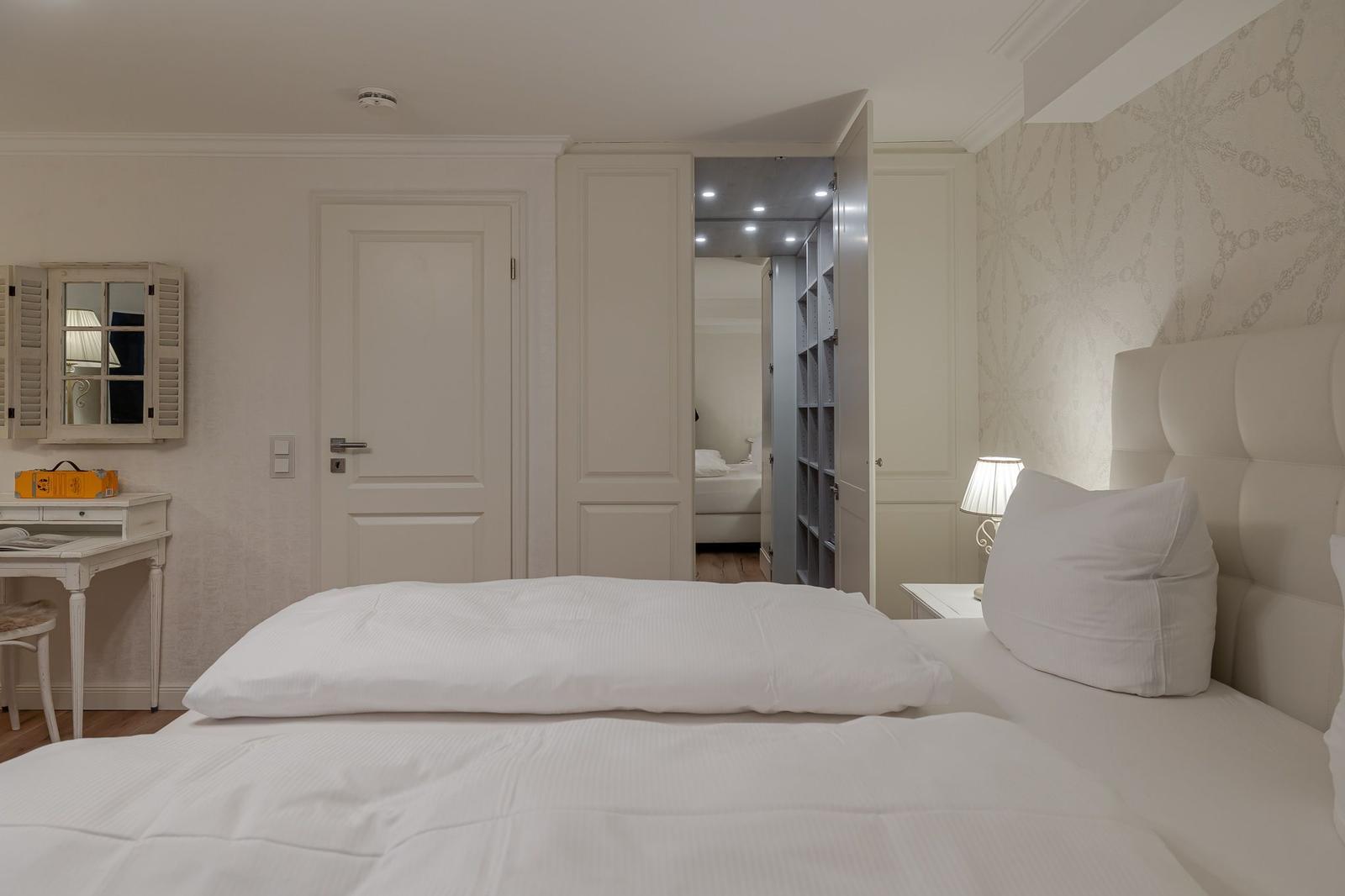 Schlafzimmer mit Bett, Schreibtisch und Kleiderschrank. Wandtapete mit Muster.
