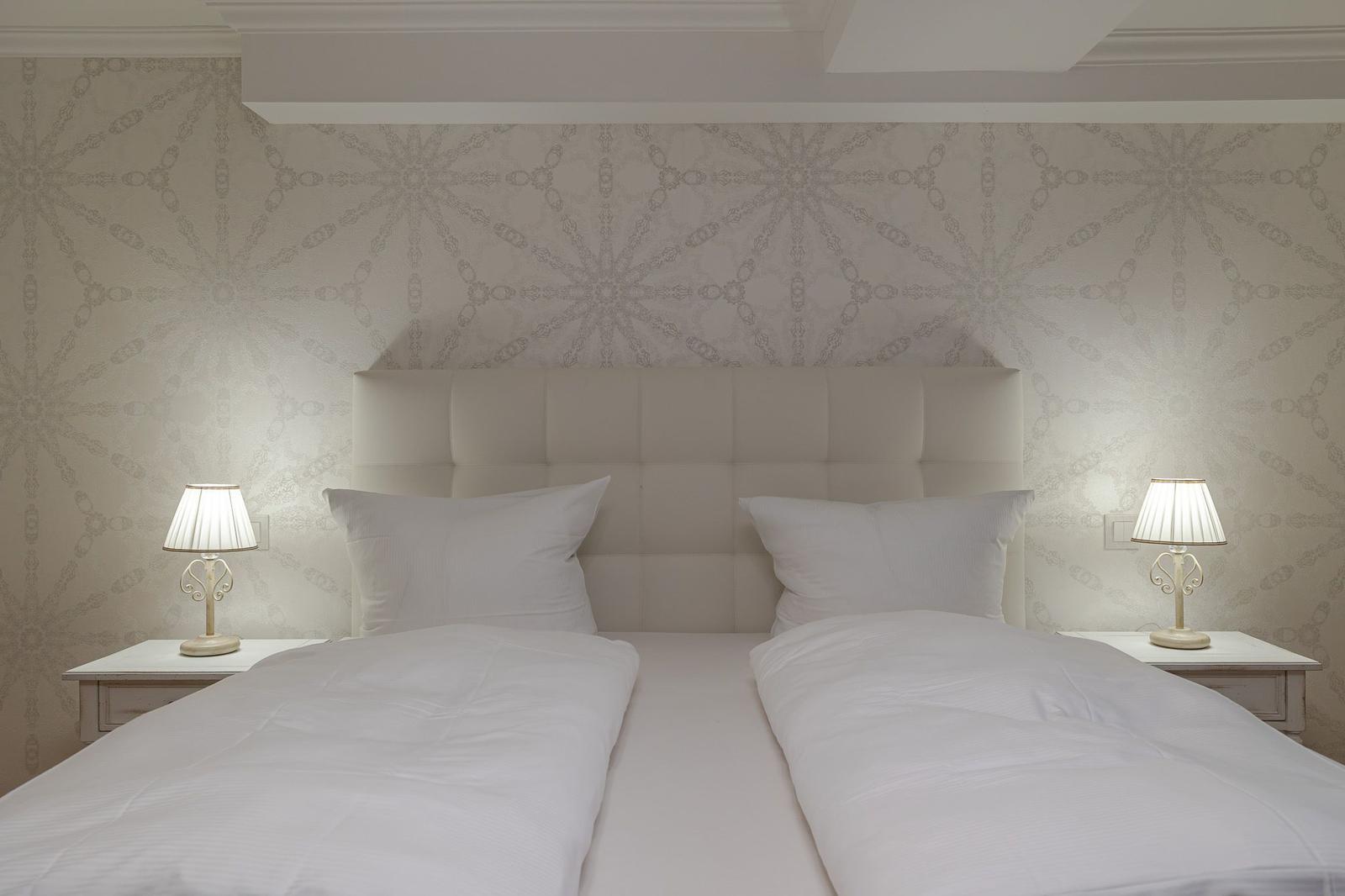Schlafzimmer mit Doppelbett, Kopfteil und zwei Nachttischen mit Lampen.