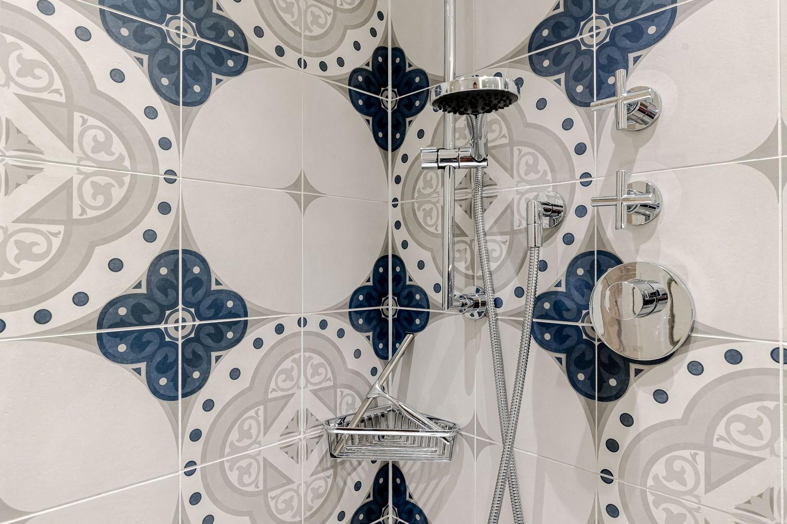 Dusche mit chromfarbenen Armaturen und dekorativen Fliesen