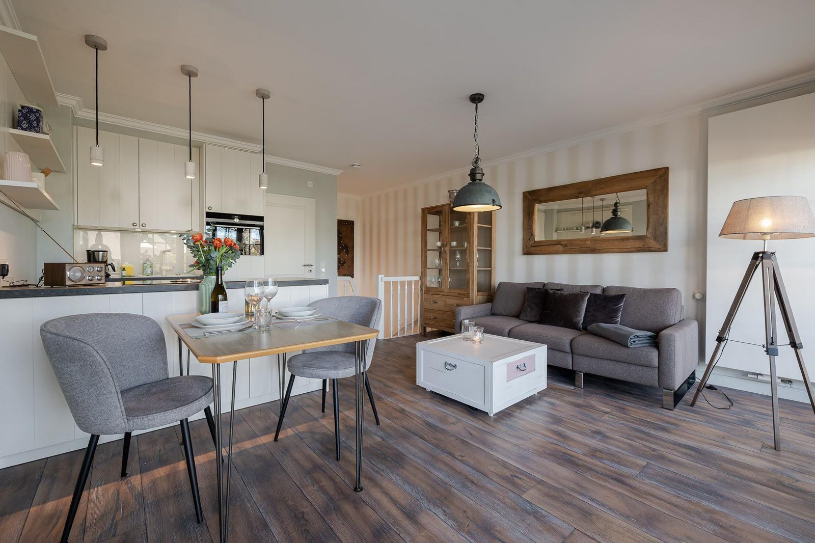 Wohn- und Essbereich mit Küchenzeile, Sofa und Holzboden.