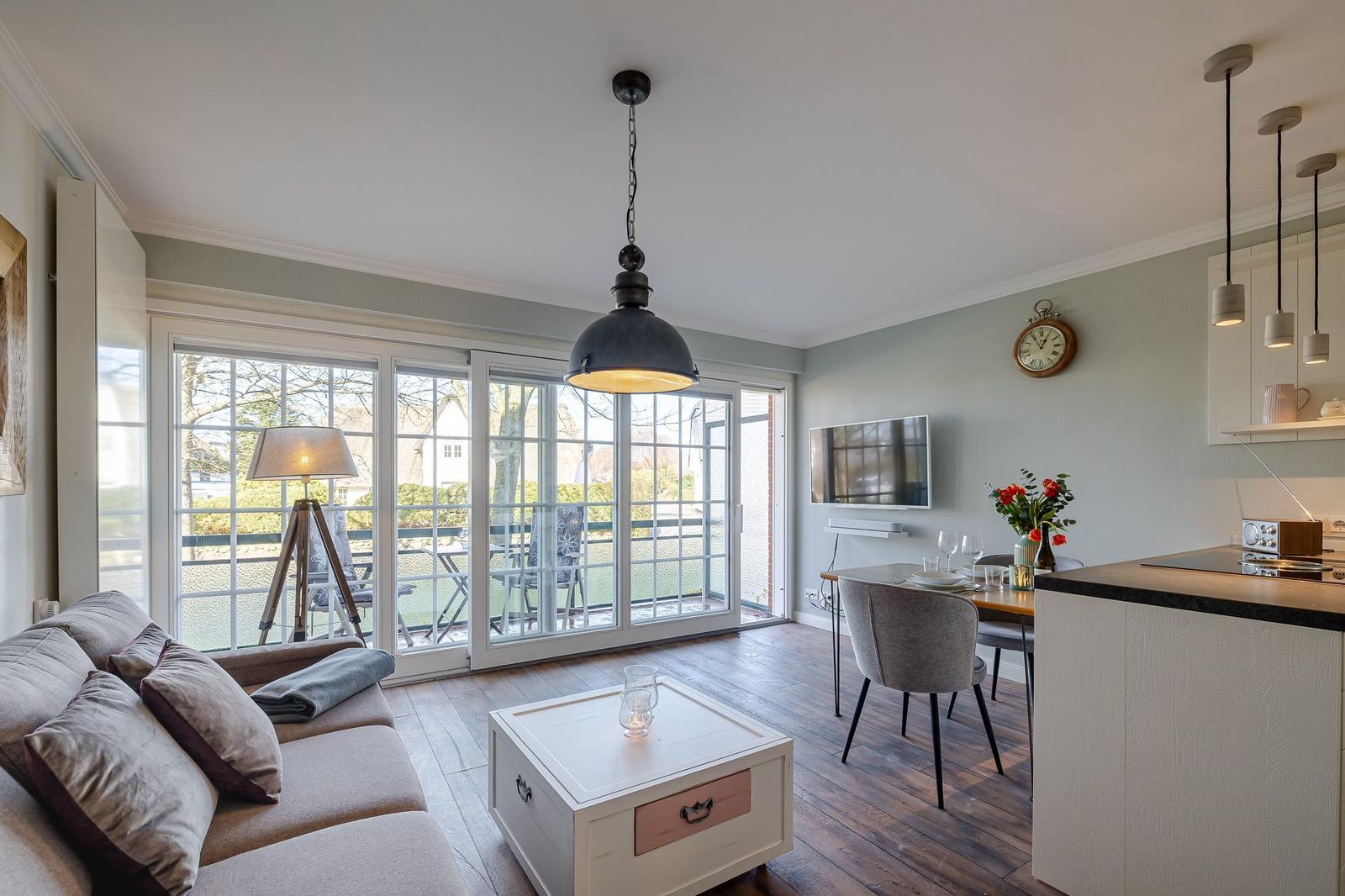 Wohn- und Essbereich mit Balkon, Sofa, Esstisch und Kücheninsel.