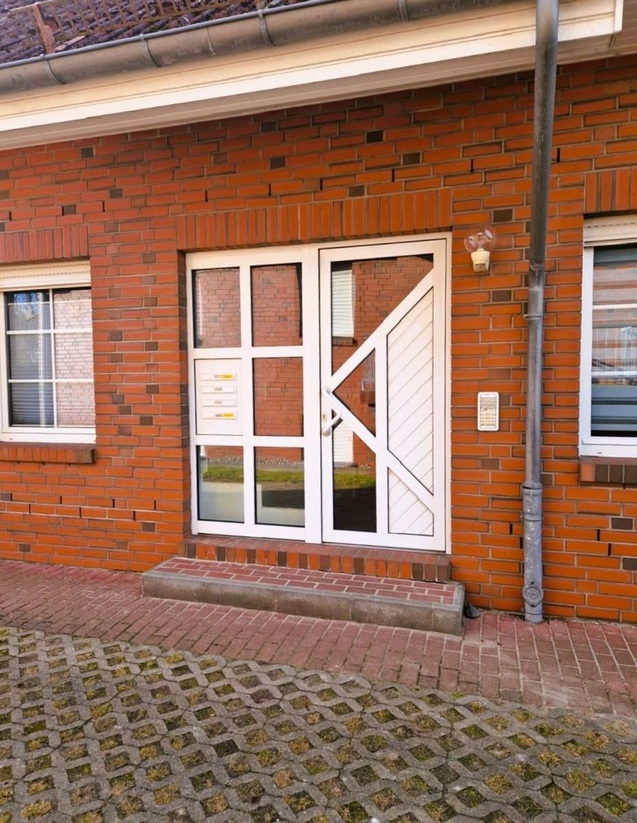 Eingangstür mit Glas und Briefkasten an rotem Backsteinhaus.