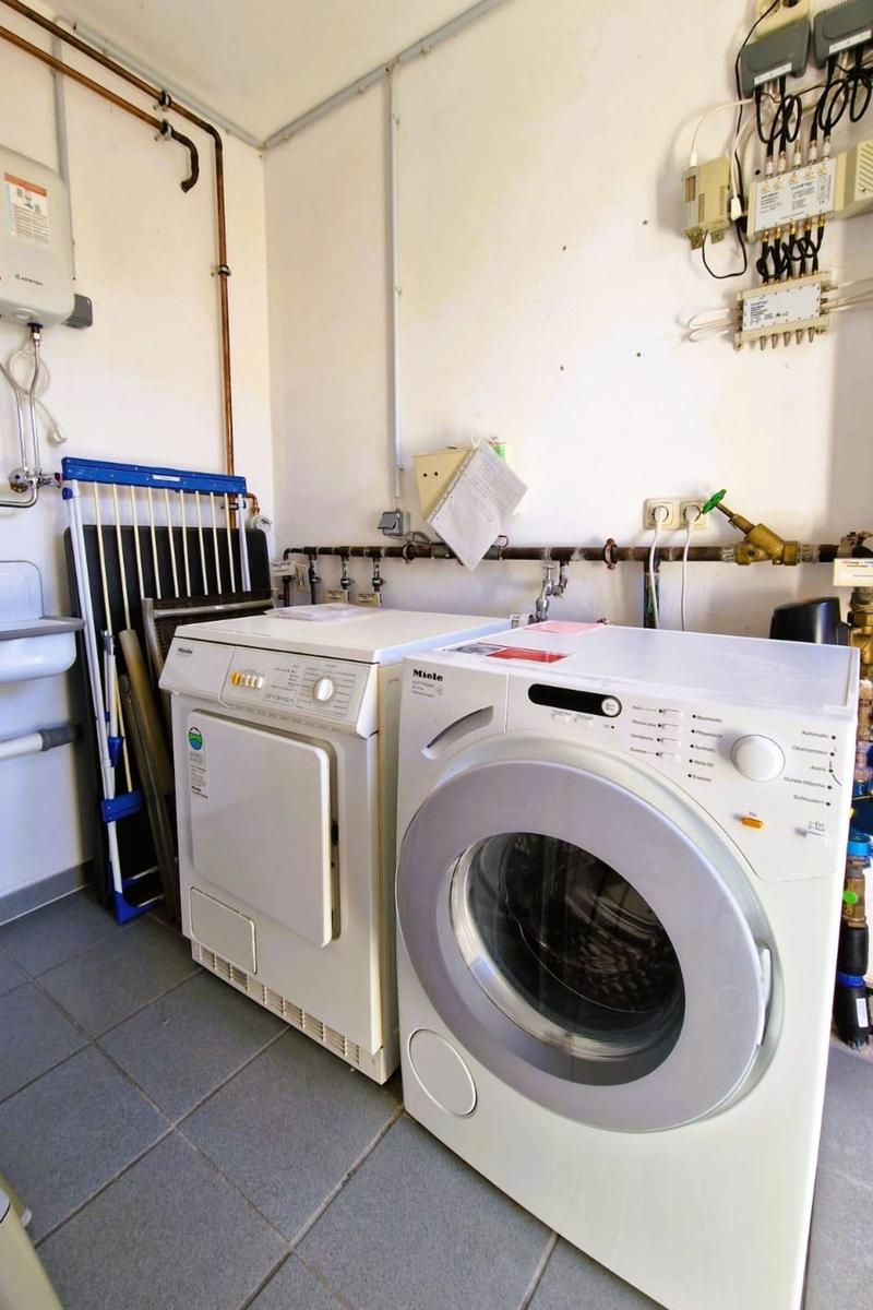 Wäscherei mit Waschmaschine und Trockner. Rohrleitungen und Steckdosen an den Wänden.