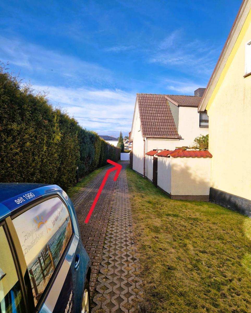 Zur Villa führt ein gepflasterter Weg zwischen Hecke und Hauswand.
