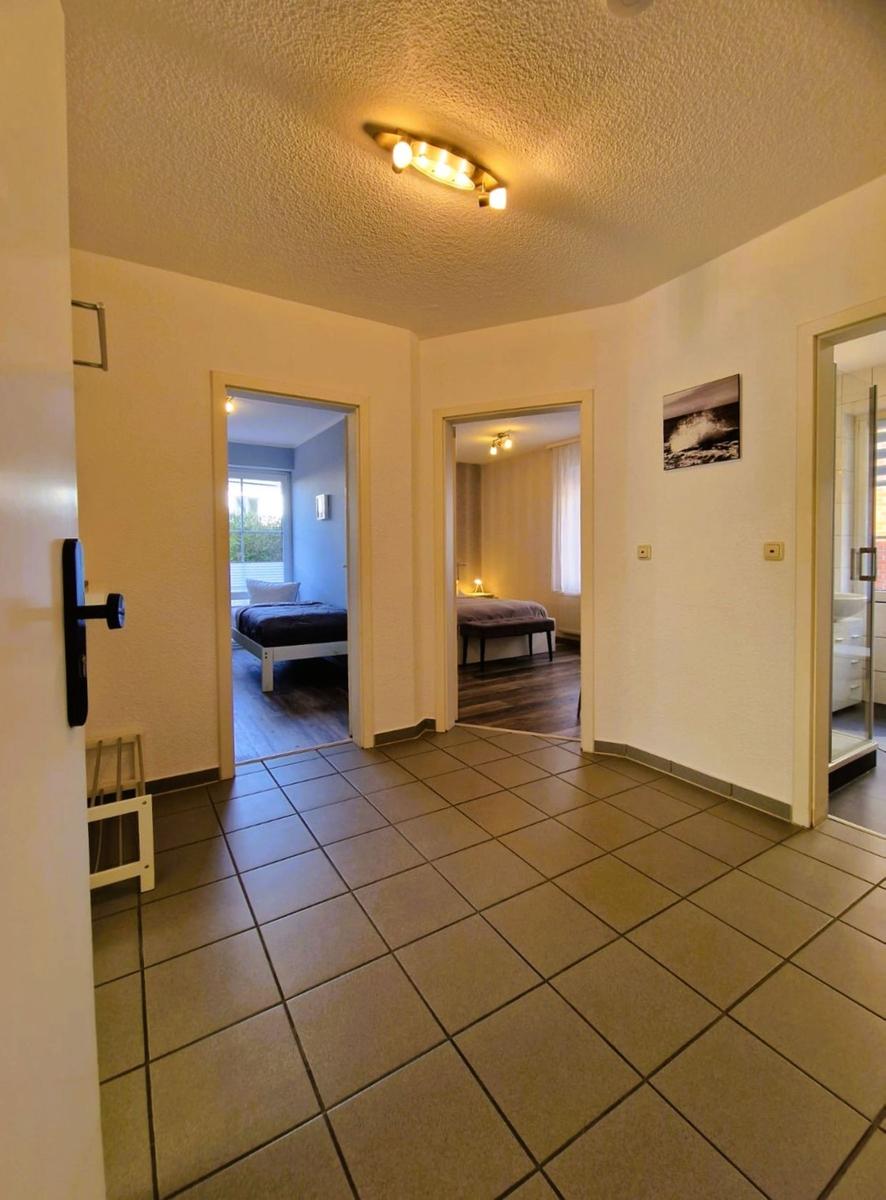 Flur mit Fliesenboden, zwei Schlafzimmer und Bad mit Dusche