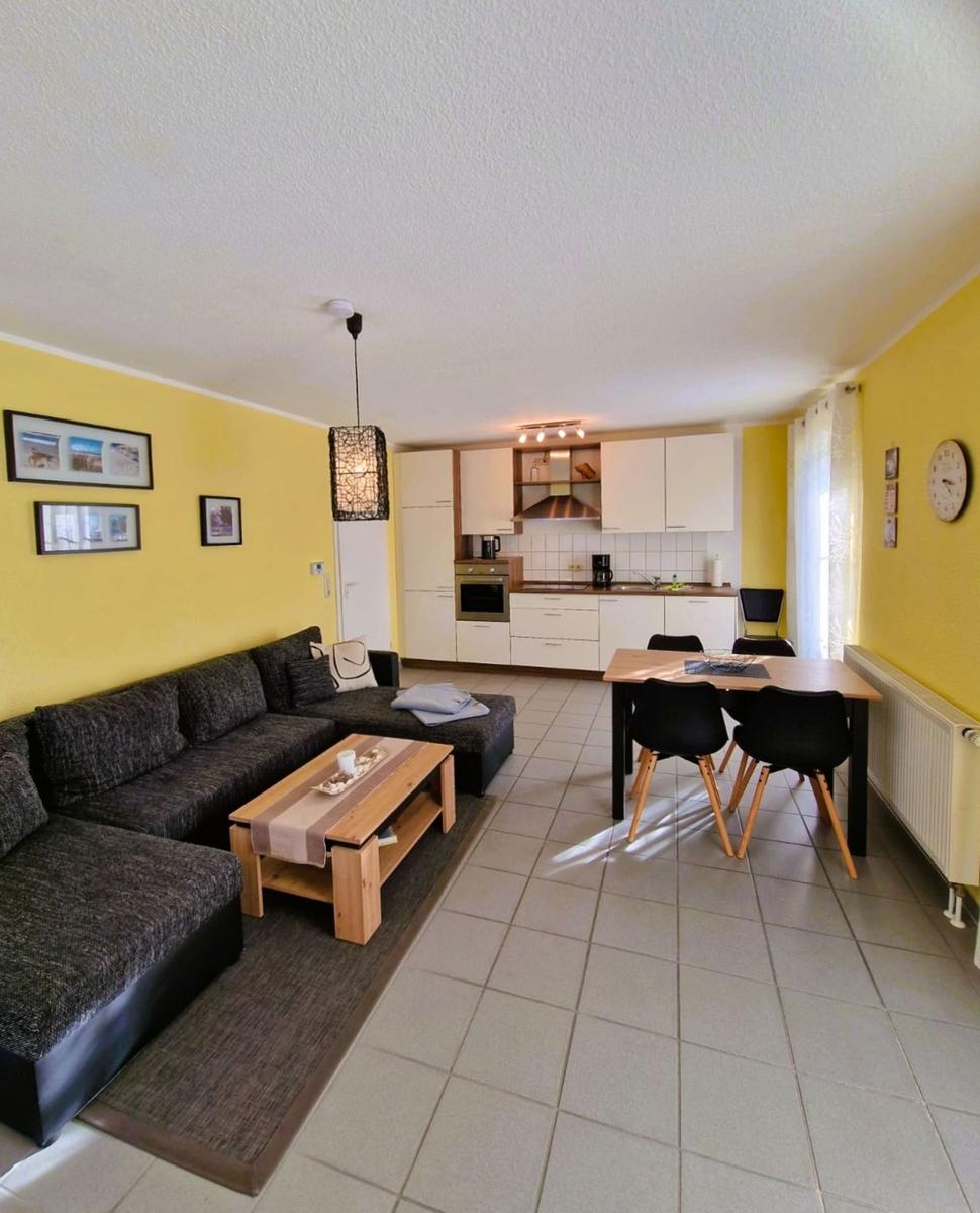 Wohn- und Essbereich mit Küchenzeile, Sofa und Tisch mit Stühlen.
