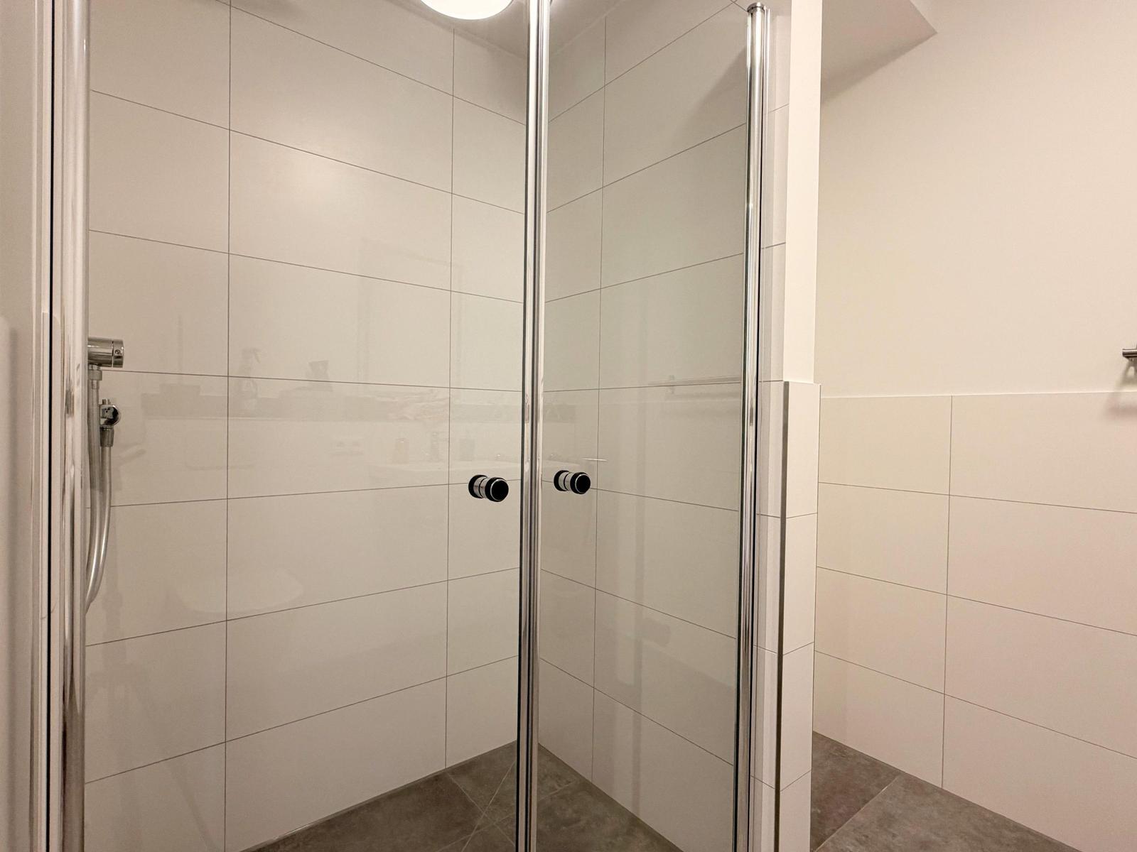 Dusche mit Glaswand und Duschbrause