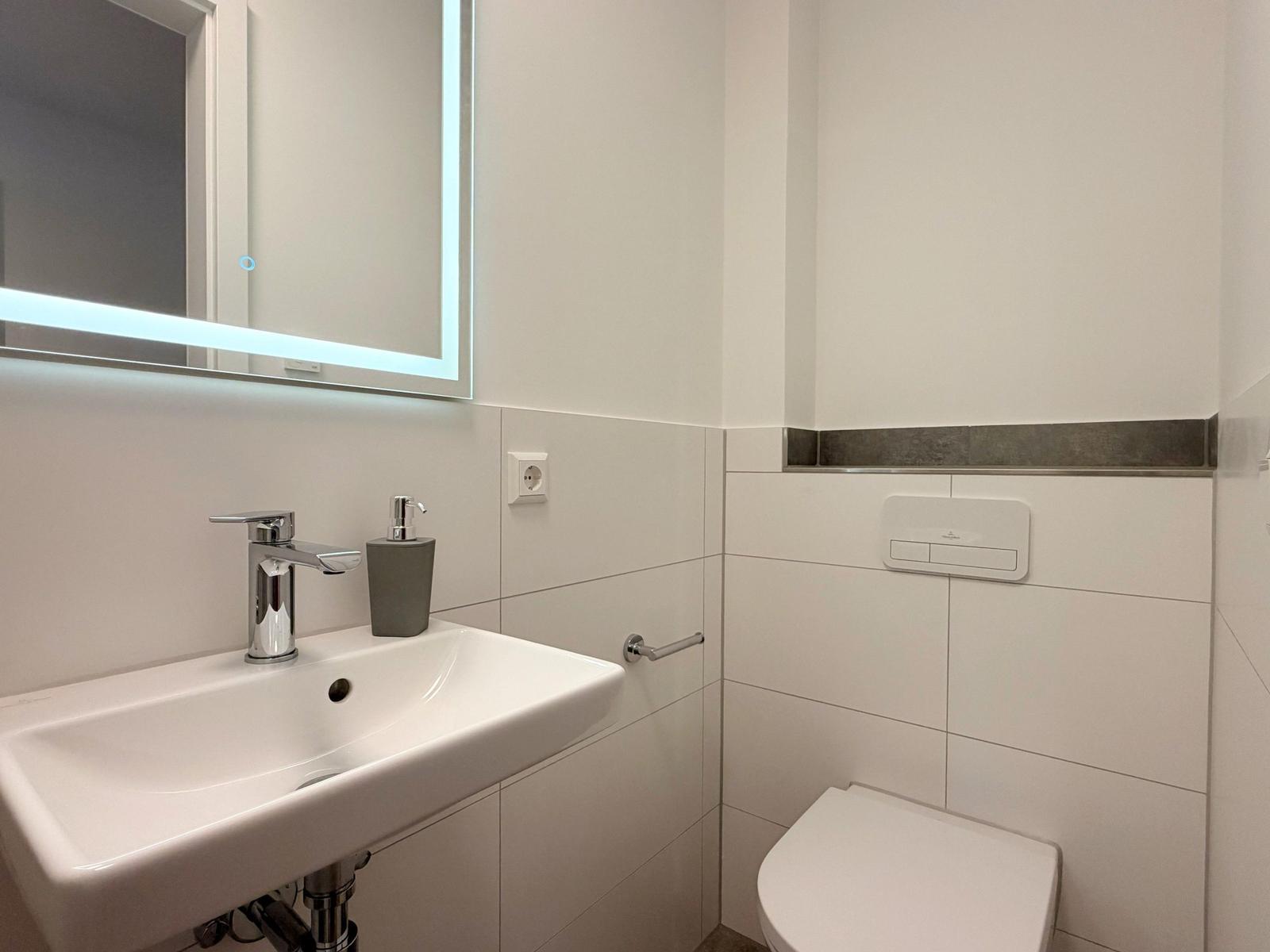Badezimmer mit Waschbecken, Spiegel und WC.