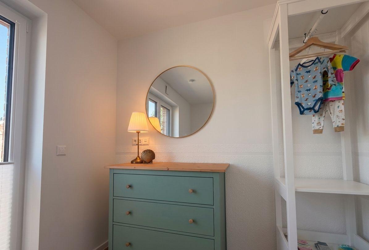 Schlafzimmer mit Kleiderschrank, Schminktisch und runden Spiegel an der Wand.