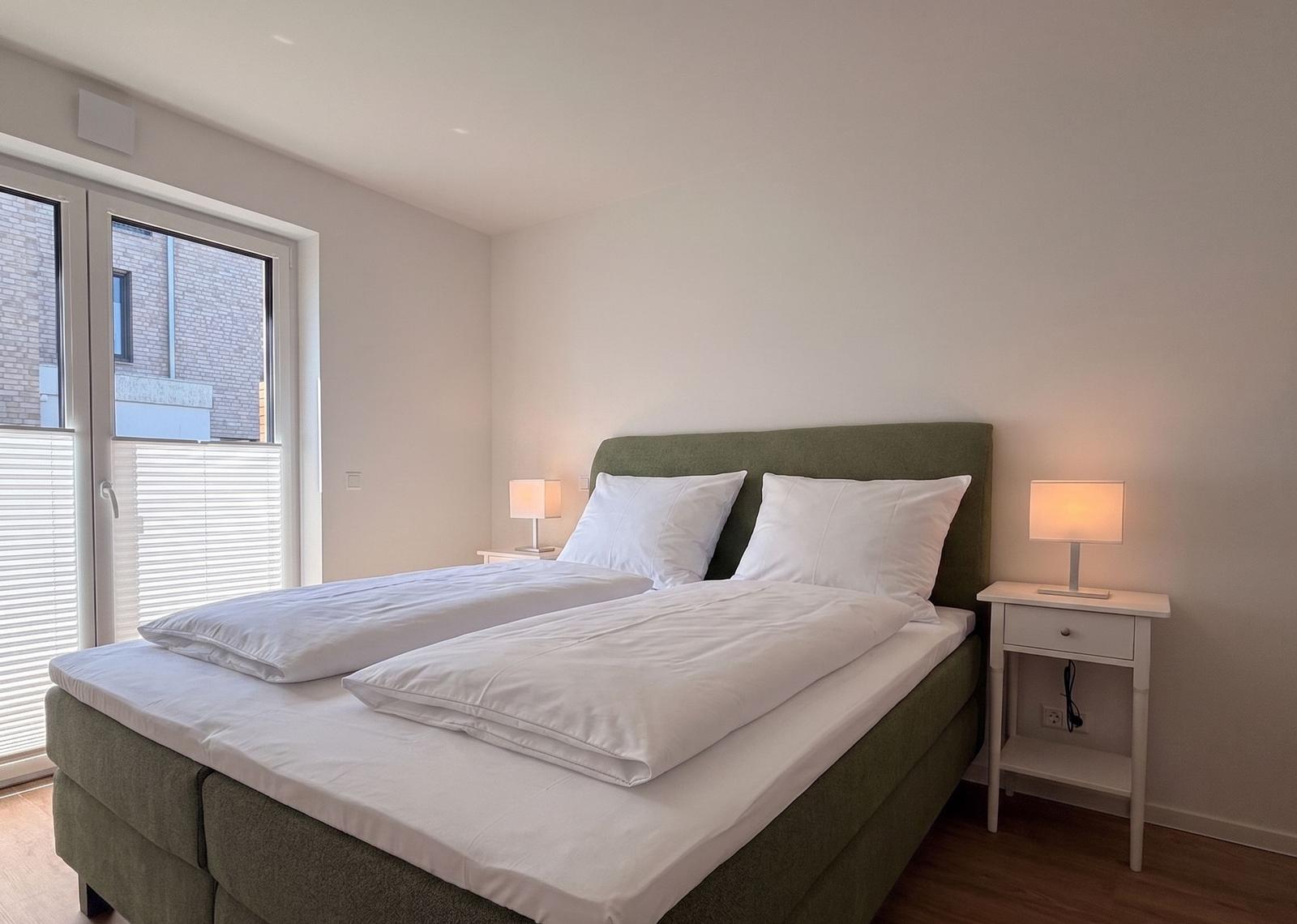 Schlafzimmer mit Doppelbett, zwei Nachttischen und Fenster.
