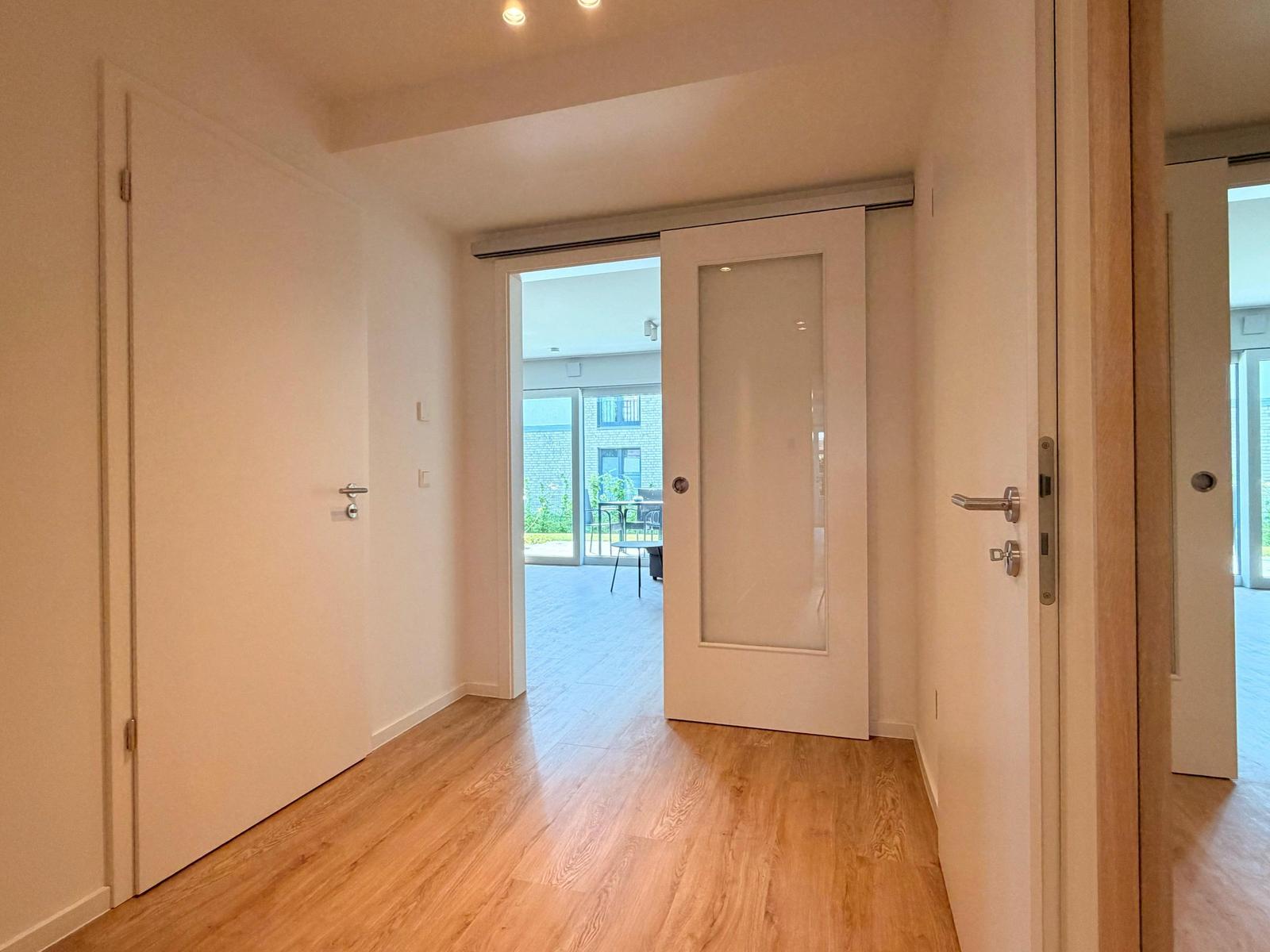 Hallenflur mit Holzboden und Türen zu Außenbereich und weiteren Räumen.