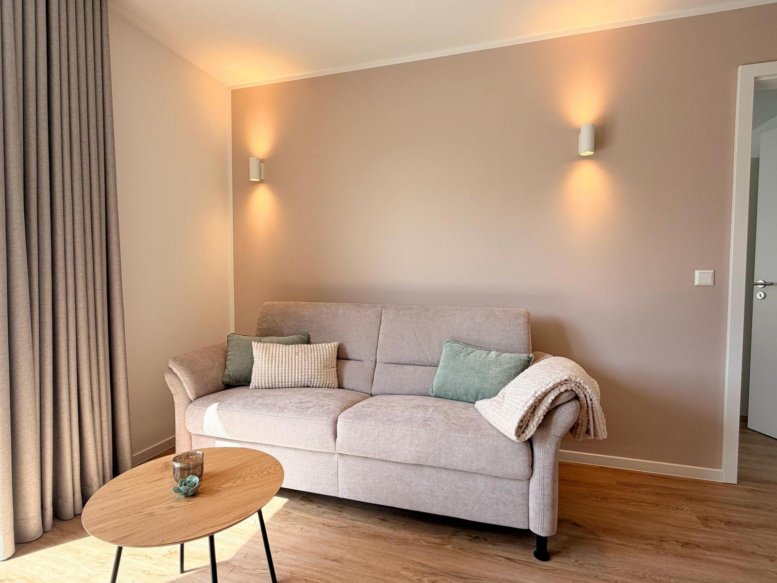 Ein Wohnzimmer mit einem Sofa, einem runden Tisch und einer Decke.