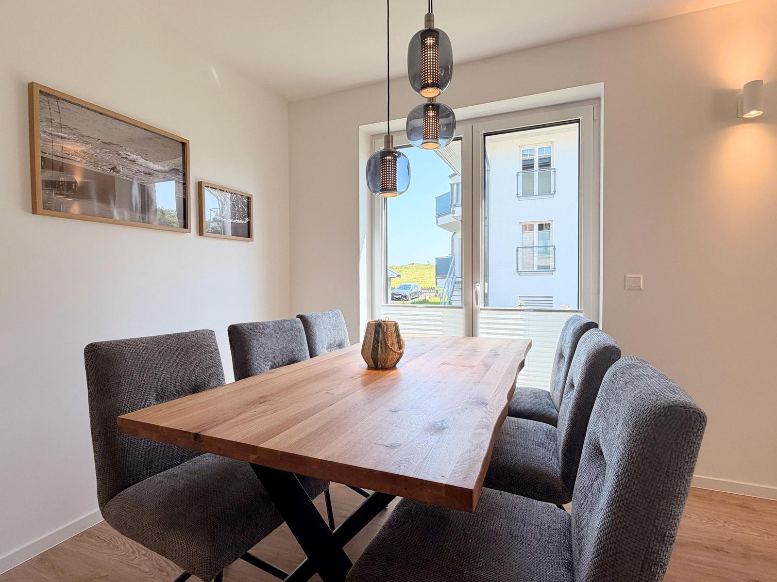Esszimmer mit Holztisch, sechs Stühlen und Fensterblick
