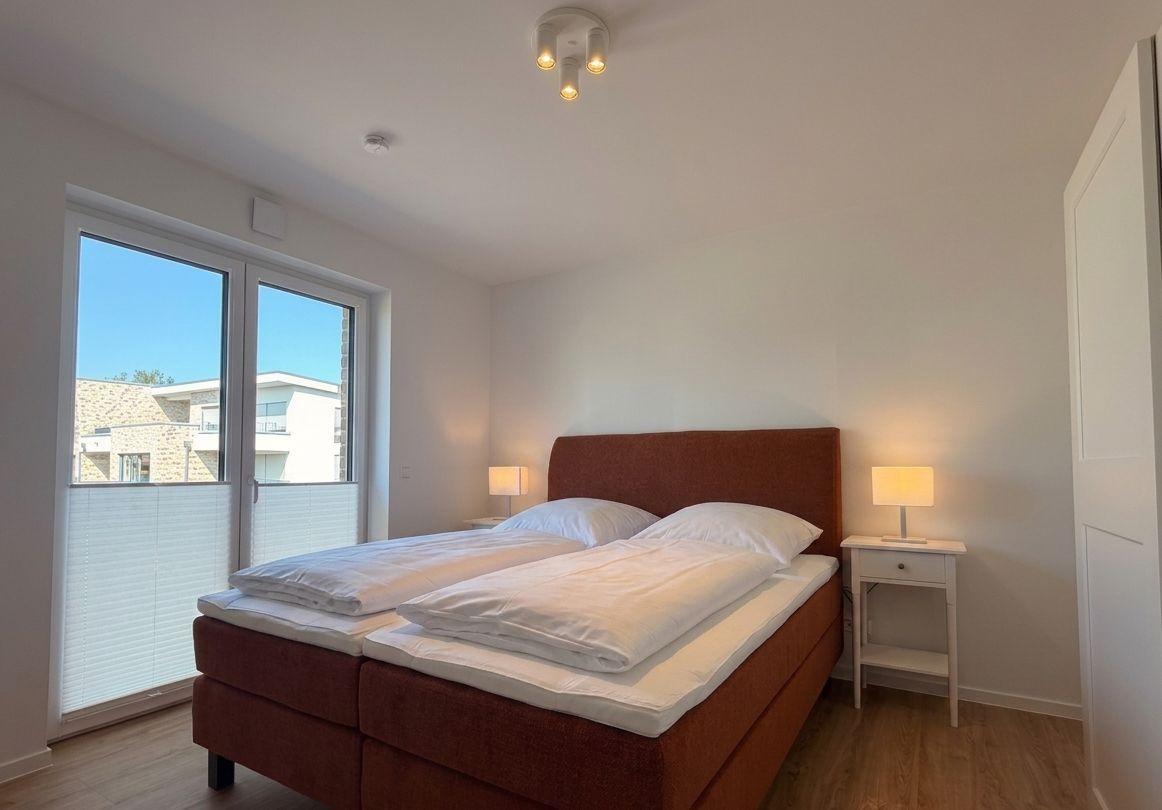 Schlafzimmer mit Doppelbett, zwei Nachttischen und Fenster zur Aussicht.